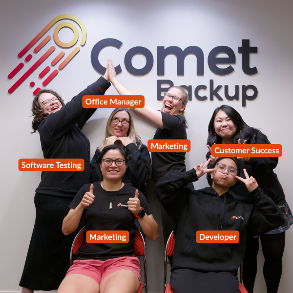Women of Comet Backup sitting in front of the company sign with funny poses
